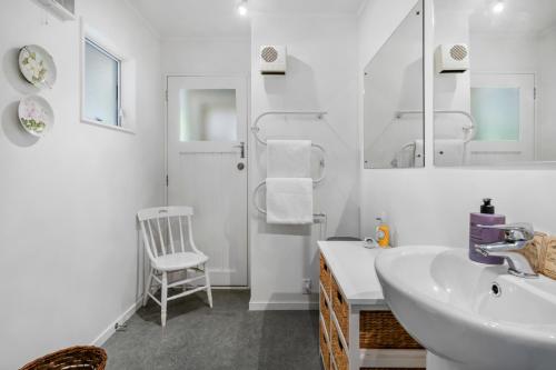baño con lavabo, espejo y silla en West and Relaxation - Greytown Holiday Home, en Greytown