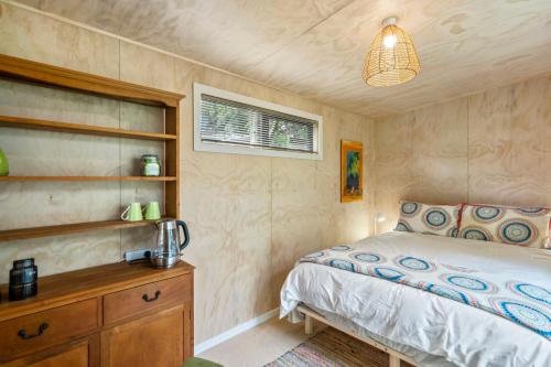 a bedroom with a bed and a wooden dresser at West and Relaxation - Greytown Holiday Home in Greytown