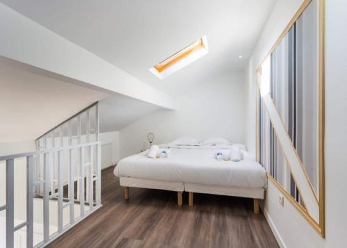 a white bedroom with a bed and a staircase at 204.Mezzanine#4Pers#Malakoff in Malakoff