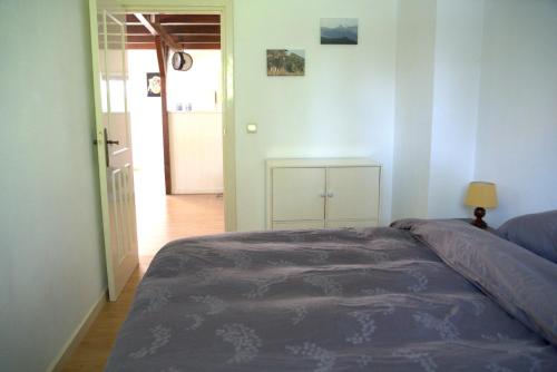 1 dormitorio con 1 cama y puerta que da a un pasillo en Sfeervolle bovenwoning uit 1916 met 2 slaapkamers, en Hooghalen