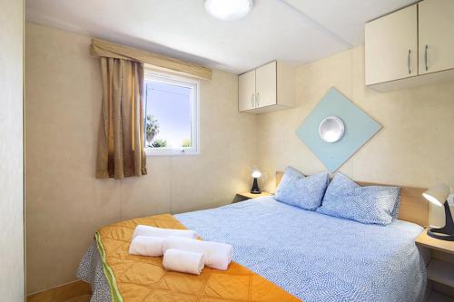 Un dormitorio con una cama con almohadas azules y una ventana en Mobile Home 1 - Olhão, en Quelfes