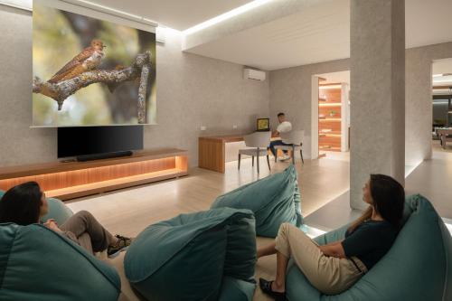 two women sitting on chairs in a living room with a tv at Amphi Exclusive Residence in Somatás