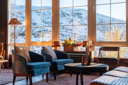 Habitación con sillas, mesa y ventanas grandes. en The Mountains Hotel, en Sierra Nevada
