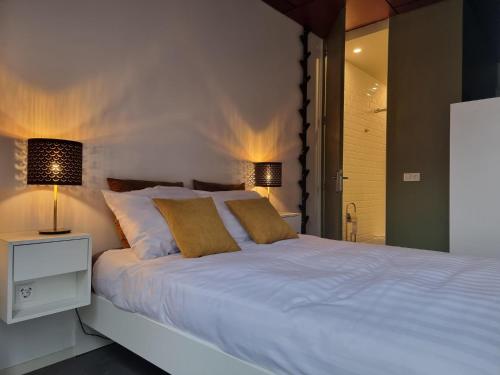 a bedroom with a large white bed with two lamps at Noordersluis Studio's in Lelystad