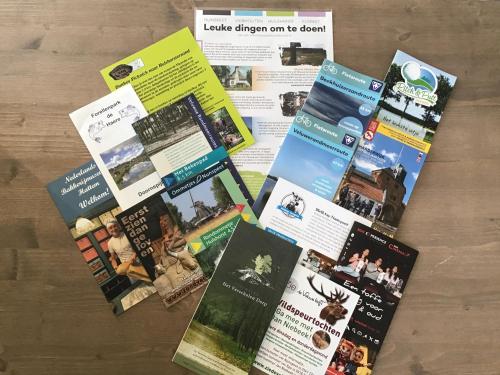 a bunch of brochures on top of a table at Vakantiehuisje B&B de Kleine Voskuil in Hulshorst