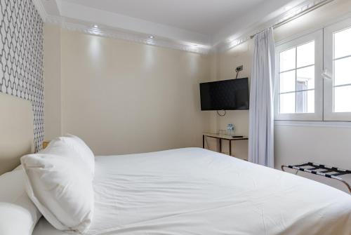 a white bedroom with a bed and a television at H-A Hotel Trebol in Málaga