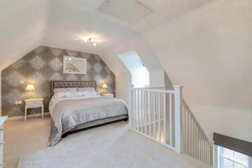 a bedroom with a large bed and a staircase at Detached family house with private garden. in Arlesey