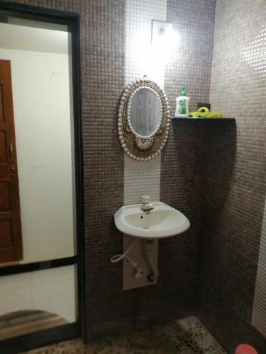 a bathroom with a sink and a mirror at Acharekar's Home stay - Adorable AC and Non AC Rooms with free Wi-Fi in Malvan