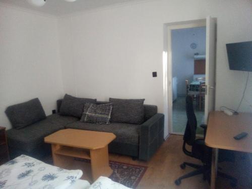 ein Wohnzimmer mit einem Sofa und einem Tisch in der Unterkunft Alpesi Trimmel Vendégház in Sopron