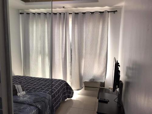 a bedroom with a bed and a tv and curtains at Birch tower by matthqueenroom, malate in Manila