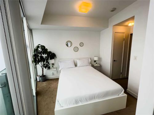 a bedroom with a white bed and a plant at Luxury Condo in the Heart of Toronto - Next to Scotiabank Arena in Toronto