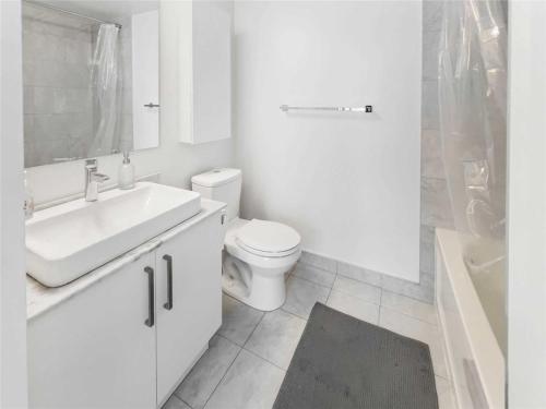 Luxury Condo in the Heart of Toronto - Next to Scotiabank Arena في تورونتو: حمام أبيض مع حوض ومرحاض