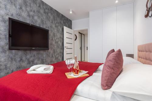 a bedroom with a red blanket on a bed with a tv at Westin House Resort Apartment Kołobrzeg by Noclegi Renters in Kołobrzeg