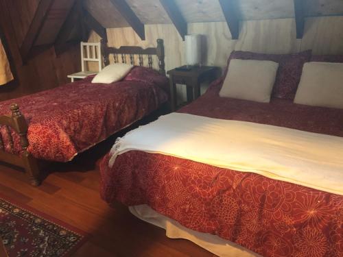 a bedroom with two beds and a table at Cabaña Ruca Quimey in Villarrica