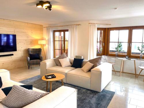 a living room with white couches and a tv at Landhaus Obermaiselstein "THE VIEW" in Obermaiselstein