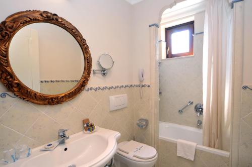 bagno con lavandino, servizi igienici e specchio di Arciduca Grand Hotel a Città di Lipari