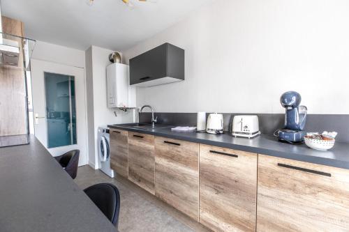a kitchen with wooden cabinets and a black counter top at L'adorable Confort & Central in Clermont-Ferrand