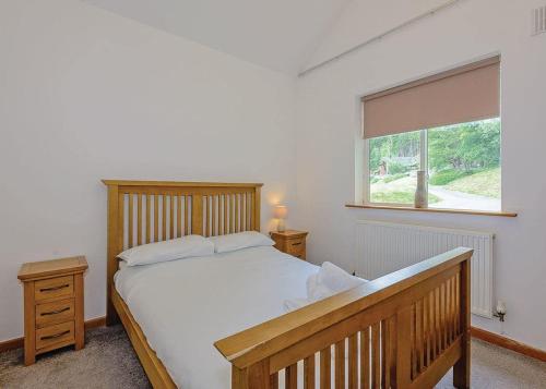 a bedroom with a wooden bed and a window at Penvale Lakes Lodges in Llangollen