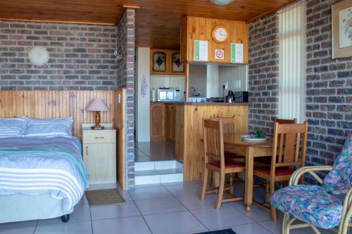 a bedroom with a bed and a table and a kitchen at Kormorant in Gansbaai