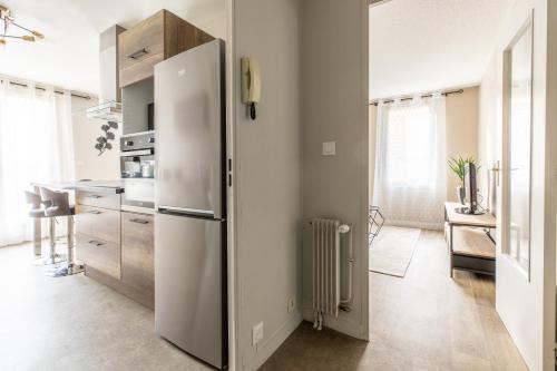a kitchen with a stainless steel refrigerator and a table at L'adorable Confort & Central in Clermont-Ferrand