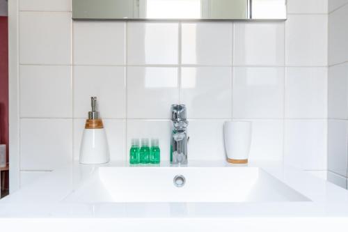 a white sink in a white tiled kitchen at L'adorable Confort & Central in Clermont-Ferrand