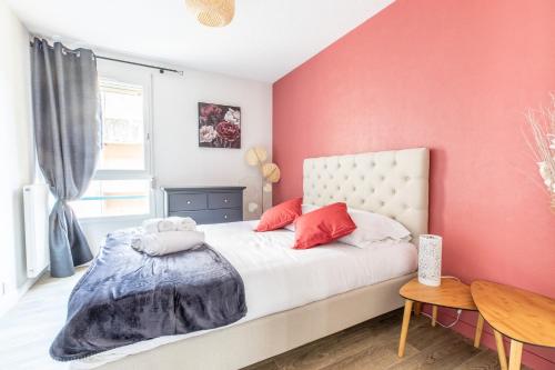 um quarto com paredes cor-de-rosa e uma cama com almofadas vermelhas em L'adorable Confort & Central em Clermont-Ferrand