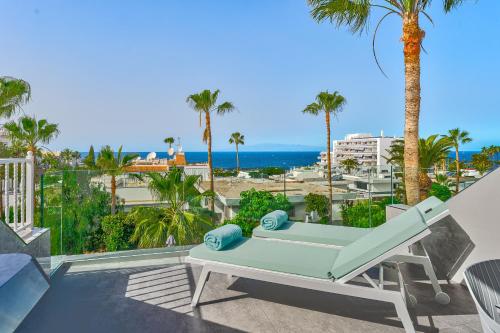 a patio with a bench and palm trees and the ocean at Ocean View Luxury Apartment PH014 in Adeje