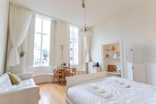 een witte slaapkamer met een wit bed en een tafel bij De Dekenije in Zutphen