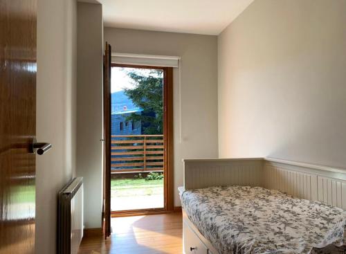 a bedroom with a bed and a sliding glass door at APARTAMENT LA MOLINA ( ELS CIRERES ) in Alp