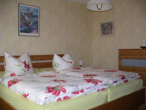 a large bed with white sheets and red flowers on it at Ferienwohnung Herrig in Treis-Karden