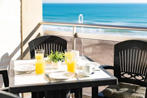 una mesa con vasos de zumo de naranja en el balcón en Apartamentos Turisticos Rent Guardamar, en Guardamar del Segura