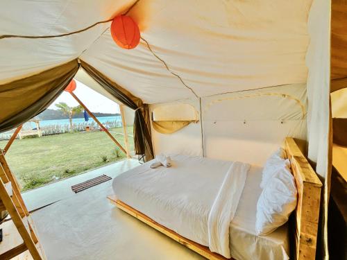 een bed in een tent met uitzicht op een veld bij Diamond Glamping by BIO Management in Tabanan