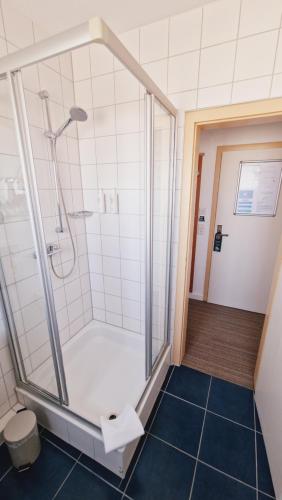 メッツィンゲンにあるHotel Garniのバスルーム(ガラスドア付きのシャワー付)
