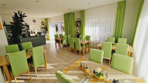 a dining room with green chairs and tables at Hotel Garni in Metzingen
