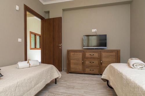 a room with two beds and a television on a dresser at Luxury Memories Villa in Nikiti