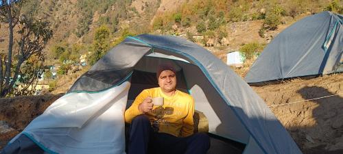 a man sitting in a tent holding a cup at Lake Haven Resort, Sari, Chopta in Sari