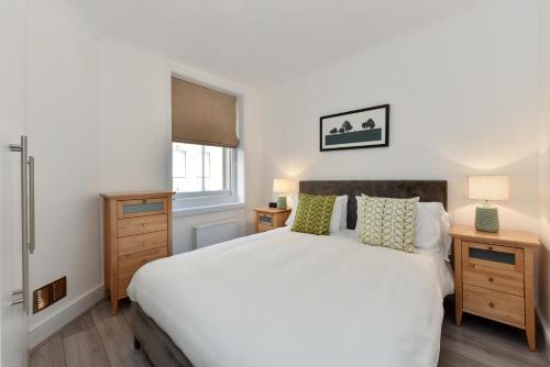 een slaapkamer met een wit bed en een raam bij Chiltern Street Serviced Apartments by Globe Apartments in Londen