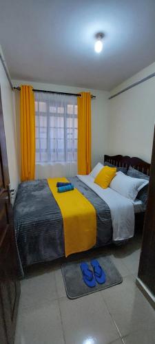 two beds in a bedroom with blue slippers on the floor at The Crystal Skep - One-bedroomed apartment in Kakamega