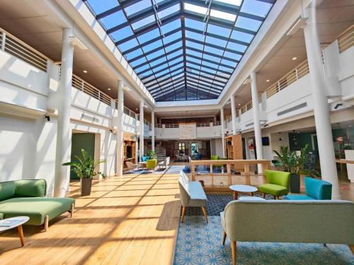 a large lobby with chairs and tables and a glass ceiling at Holiday Inn Calais Coquelles, an IHG Hotel in Coquelles