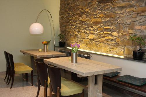 two tables and chairs in a room with a stone wall at Alt pension in Prague