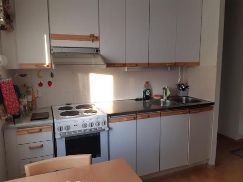 uma cozinha com armários brancos, um fogão e um lavatório em Savonlinnan keskusta em Savonlinna