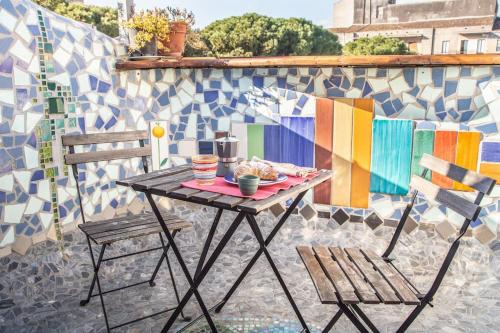einen Tisch und Stühle auf einer Terrasse mit Mosaikwand in der Unterkunft Casa Verde in Catania