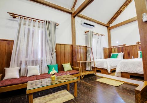 Habitación con 2 camas, sofá y mesa. en Maison Model d'Angkor, en Siem Reap