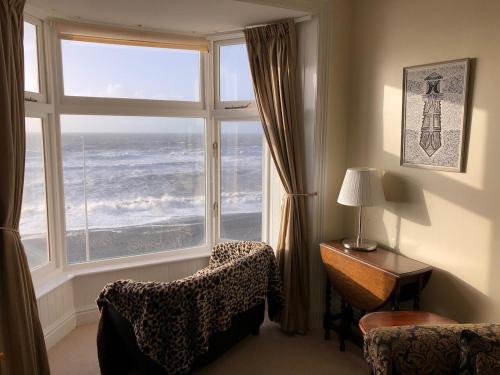 a room with a large window and a chair and a table at Stunning Aberystwyth South Beach Apartment in Aberystwyth