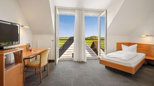 a hotel room with a bed and a desk and a window at Landhotel Beck in Kupferzell