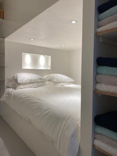 a bedroom with a white bed with a shelf with towels at hip & stylish apartment in center, near trainstation, 15 min walk in Amsterdam