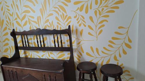 een houten stoel en twee krukken voor een muur bij CASA AZUL in Peruíbe