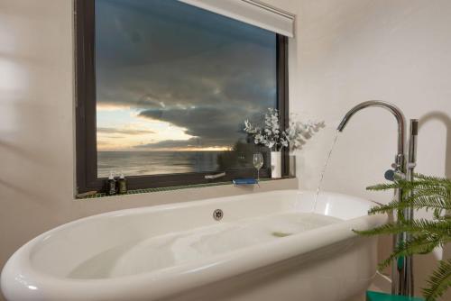 a bath tub in a bathroom with a window at Little Cottage in Praa Sands