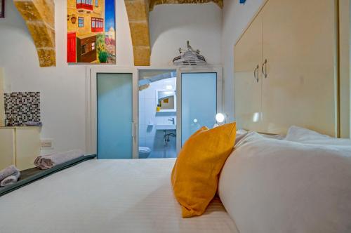 a bedroom with a white bed with a yellow pillow at Sally Port 32 in Valletta