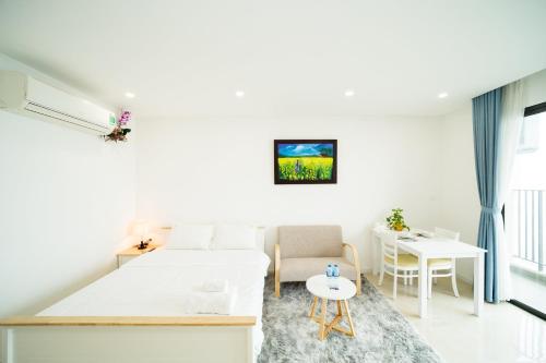 een witte slaapkamer met een bed, een tafel en een bureau bij Vinhomes D’capitale studio in Hanoi